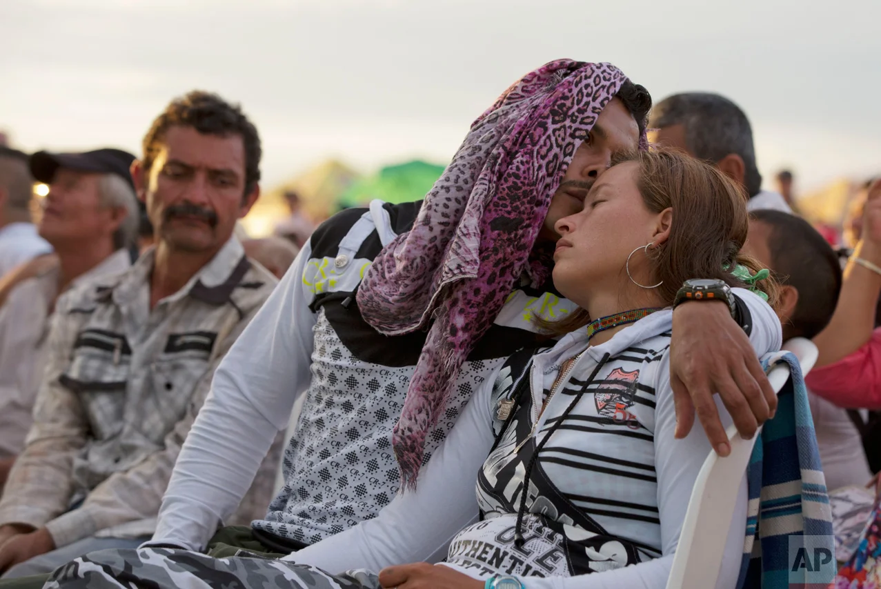 In this Sept. 26, 2016 photo, rebels of the Revolutionary Armed Forces of Colombia, FARC, embrace in Yari Plains, southern Colombia, as they watch the ceremony where President Juan Manuel Santos and FARC leader Rodrigo Londono, signed a peace accord to end more than five decades of conflict in the Caribbean city of Cartagena. In late November, Santos signed a new peace agreement with the country's largest rebel movement nearly two months after the original deal was rejected in a referendum. (AP Photo/Ricardo Mazalan)