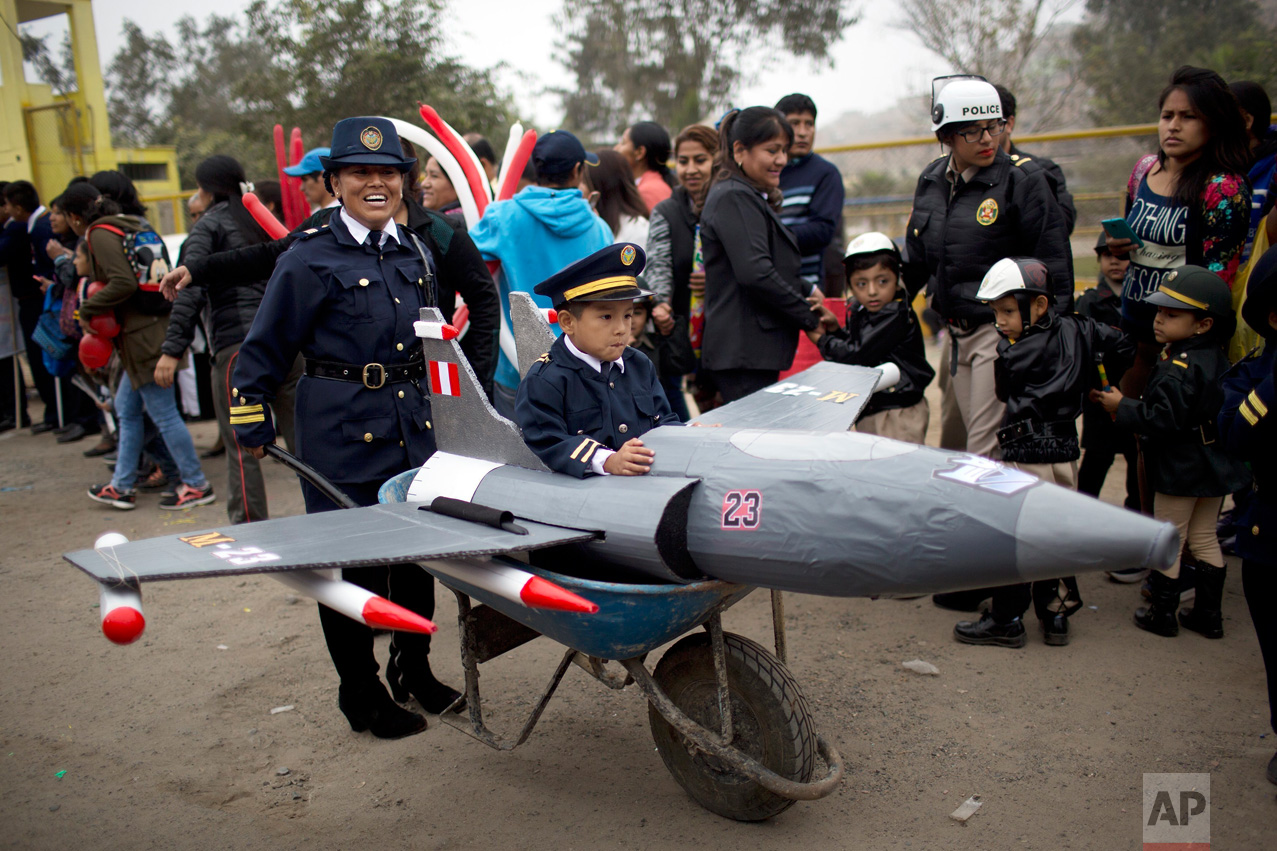  In this June 3, 2016 photo, a teacher pushes her student in a wheelbarrow decorated as a plane, during a parade organized by the Valderrama school ahead of National Flag Day in the Villa el Salvador district of Lima, Peru. The South American country