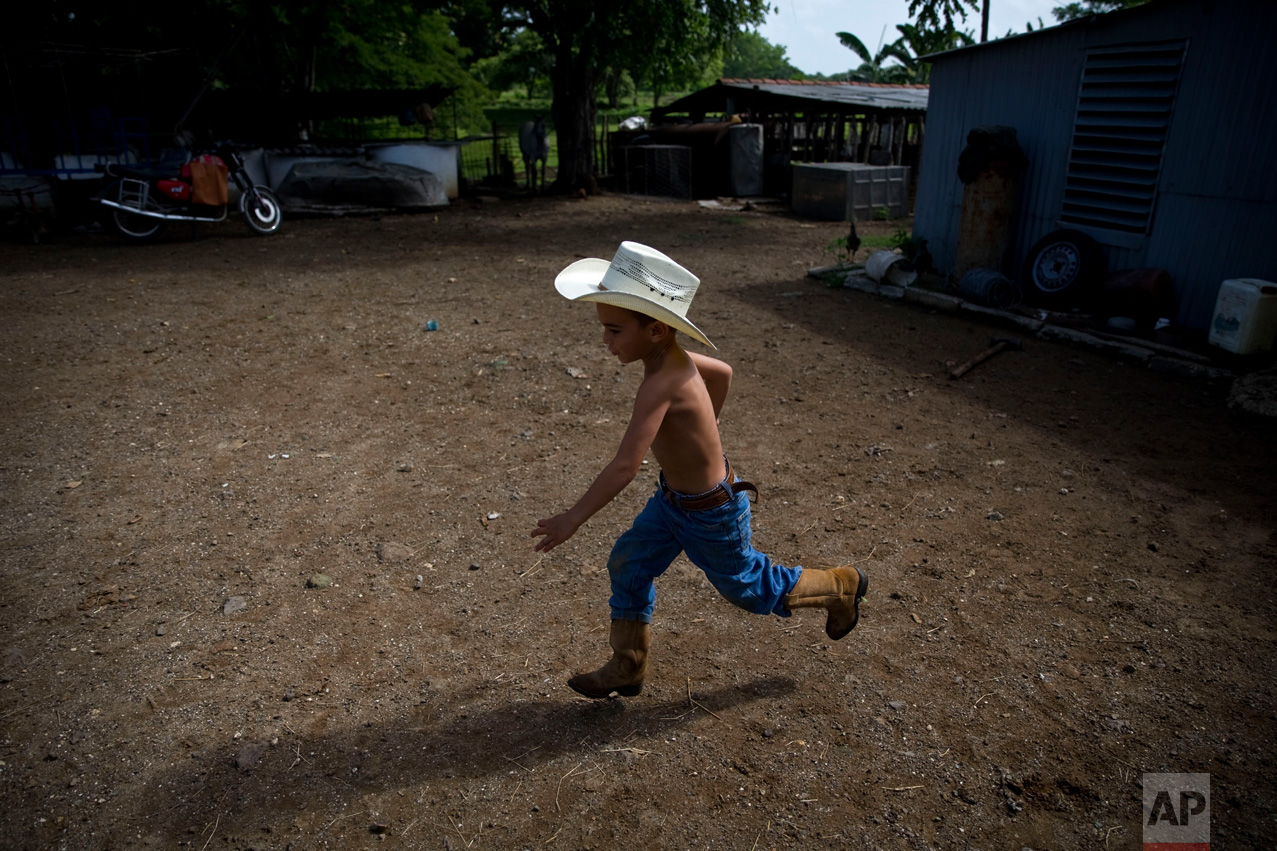  In this July 29, 2016 photo, 5-year-old cowboy David Obregon runs across his yard at his parent's farm in Sancti Spiritus, central Cuba. In the Cuban countryside, many children learn to ride a horse before they learn to ride a bicycle. Those who gro