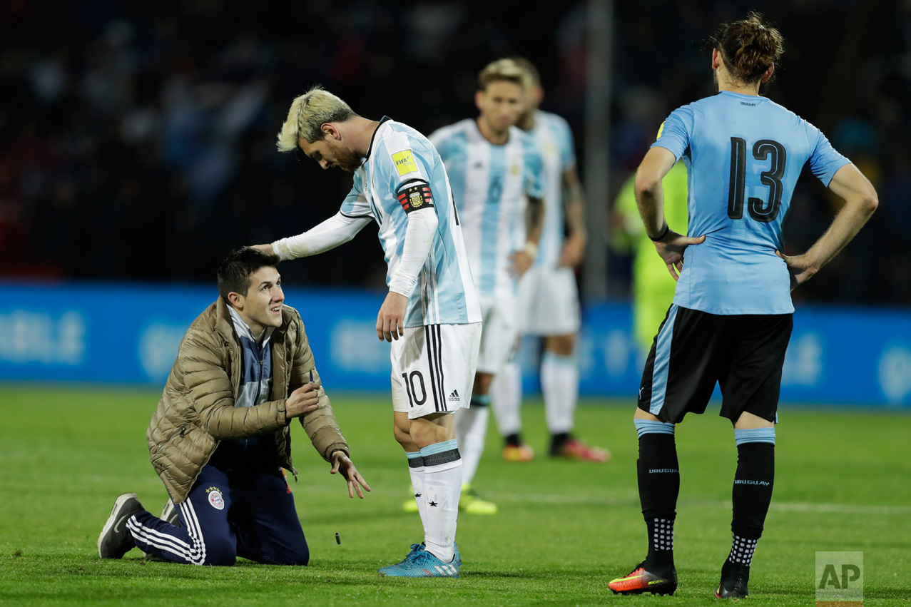  In this Sept. 1, 2016 photo, a fan who invaded the pitch kneels in front of Argentina's Lionel Messi, center, as Uruguay's Gaston Silva looks on during a 2018 World Cup qualifying soccer match in Mendoza, Argentina. Argentina won the match 1-0. (AP 
