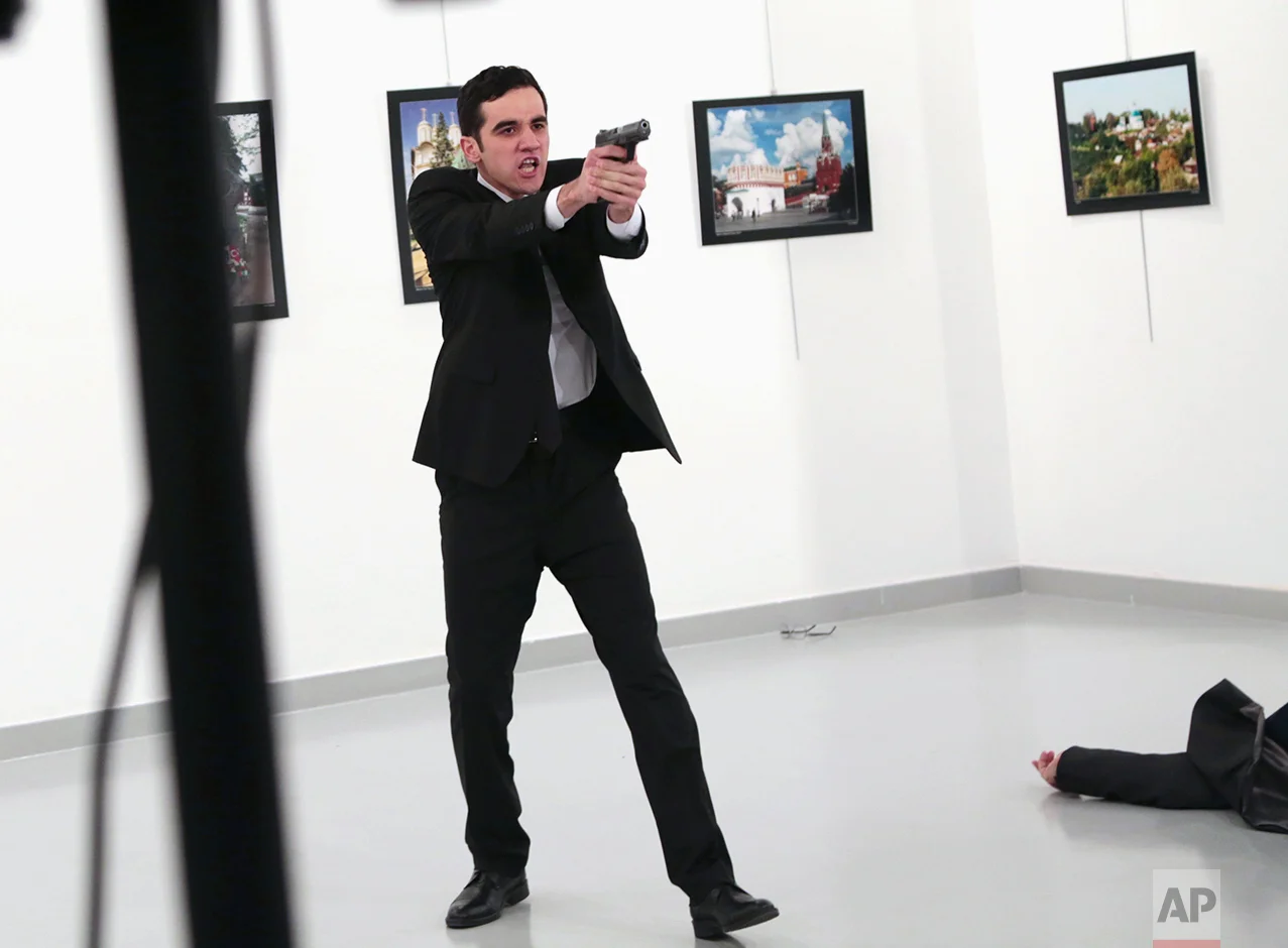A man identified as Mevlut Mert Altintas gestures after shooting Andrei Karlov, the Russian Ambassador to Turkey, on the floor, at a photo gallery in Ankara, Turkey, Monday, Dec. 19, 2016. (AP Photo/Burhan Ozbilici)