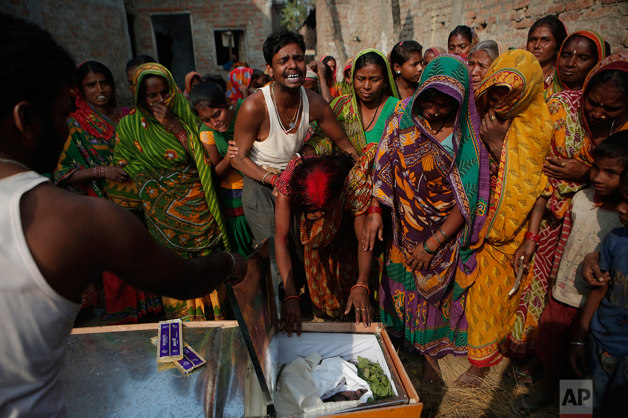 In this Wednesday, Nov. 23, 2016 photo, Saro Kumari Mandal, 26, cries as she leans on the coffin carrying her husband Balkisun Mandal Khatwe, 26, a migrant worker who died in his sleep in Qatar, at Belhi village, in Saptari district, Nepal. The number of Nepali workers going abroad has more than doubled since the country began promoting foreign labor in recent years: from about 220,000 in 2008 to about 500,000 in 2015. Yet the number of deaths among those workers has risen much faster in the same period. But now medical researchers say these deaths fit a familiar pattern: Every decade or so, dozens, or even hundreds, of seemingly healthy Asian men working abroad in poor conditions start dying in their sleep. The suspected killer even has a name: Sudden Unexplained Nocturnal Death Syndrome. (AP Photo/Niranjan Shrestha)