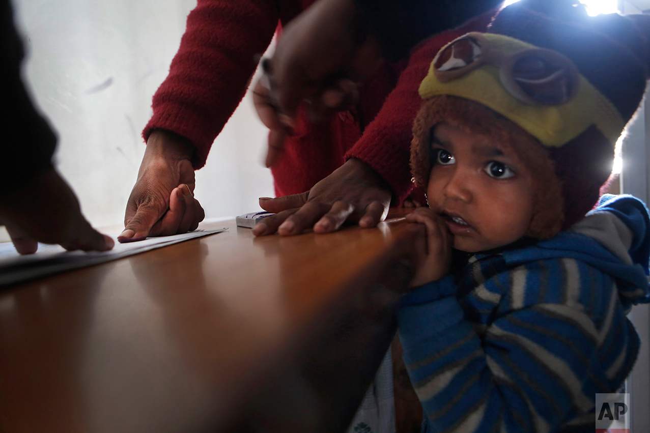 In this photo taken on Monday, Dec 19, 2016, Saro Kumari Mandal, 26, gives her thumb impression to receive compensation after her husband died as a migrant worker in Qatar, as her son stands by her side at the Department of Foreign Employment in Kathmandu, Nepal. Saro received $2,777 from the Foreign Employment Promotion Board. She said she would use the money to open a small store in the village selling cookies and noodles, and also invest in a sewing machine. She wants to earn money for their son's education. "I want to make my son a teacher or a doctor when he grows up," she said. (AP Photo/Niranjan Shrestha)