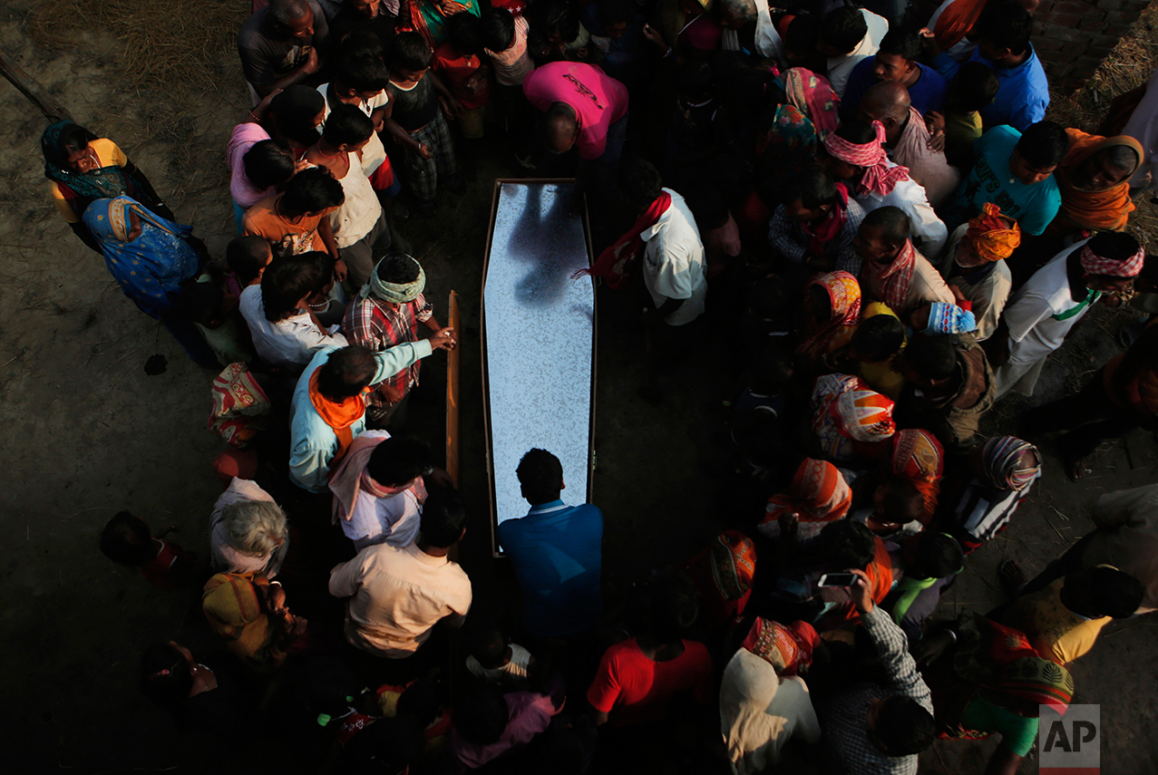 In this Nov. 23, 2016 photo, relatives and villagers gather around the coffin of Balkisun Mandal Khatwe at Belhi village, Saptari district of Nepal. Balkisun, who had been working for Habtoor Leighton Group in Qatar for less than a month, died in his sleep. The number of Nepali workers going abroad has more than doubled since the country began promoting foreign labor in recent years: from about 220,000 in 2008 to about 500,000 in 2015. Yet the number of deaths among those workers has risen much faster in the same period. In total, over 5,000 workers from this small country have died working abroad since 2008, more than the number of U.S. troops killed in the Iraq War. (AP Photo/Niranjan Shrestha)