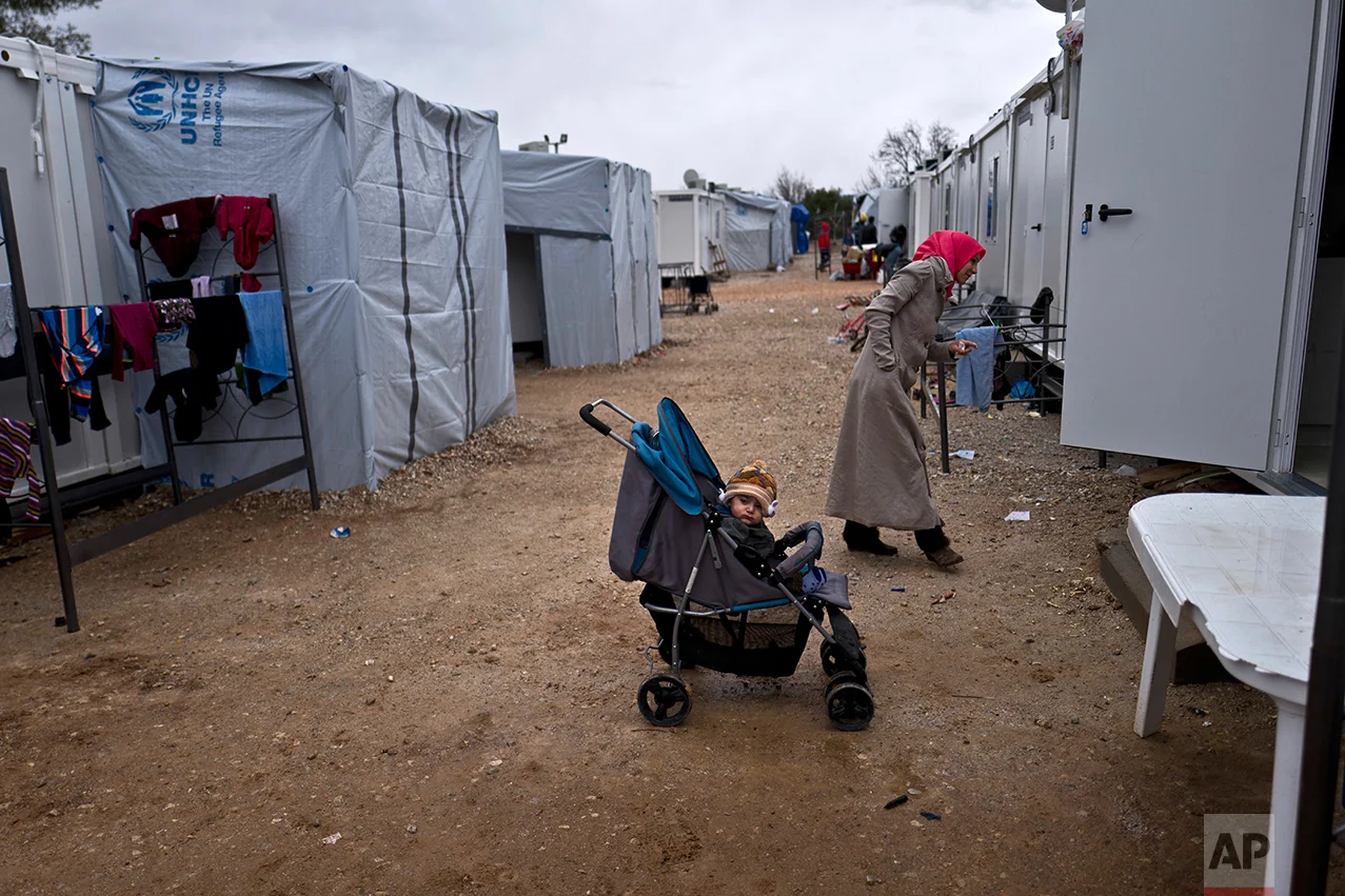 Syrian refugee child Alan Jouva, 2, sits in a stroller outside his family's shelter at the refugee camp of Ritsona about 86 kilometers (53 miles) north of Athens, Wednesday, Dec. 28, 2016. (AP Photo/Muhammed Muheisen)