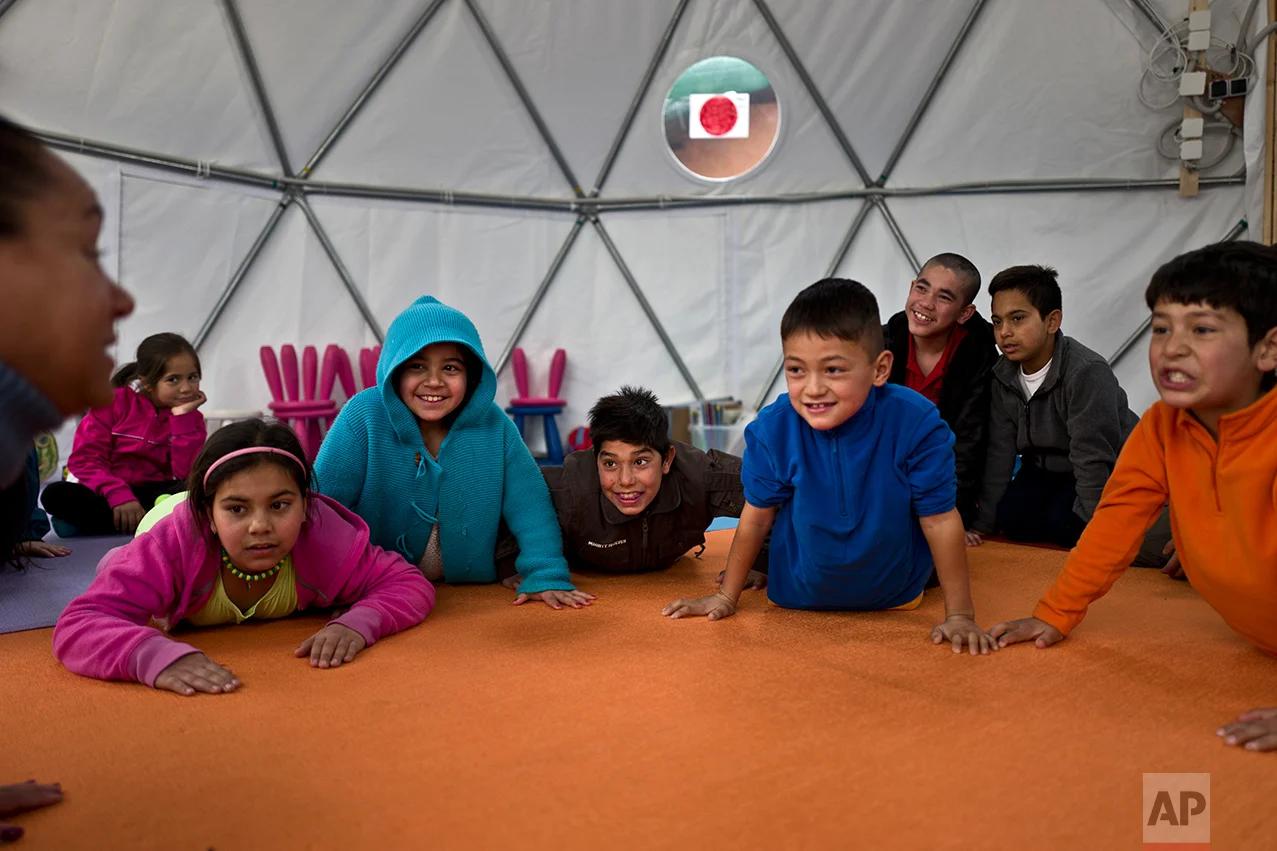 Afghan refugee children attend a yoga session during a class at a makeshift school in the refugee camp of Oinofyta about 58 kilometers (36 miles) north of Athens, Tuesday, Dec. 27, 2016. (AP Photo/Muhammed Muheisen)