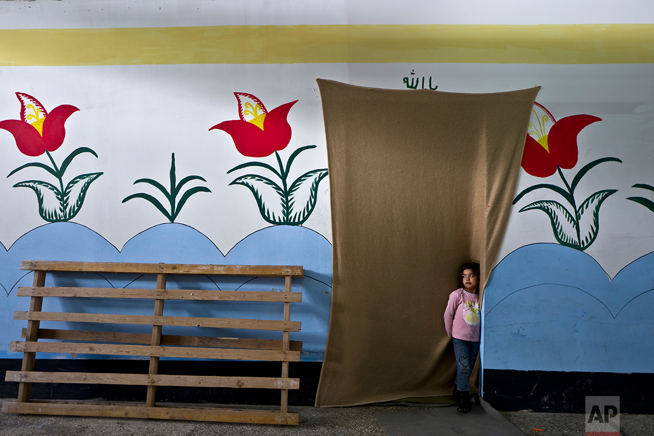  Tharwat, a 6-year-old Afghan refugee girl stands at the doorway of her family's shelter at the refugee camp of Oinofyta about 58 kilometers (36 miles) north of Athens, Tuesday, Dec. 27, 2016. (AP Photo/Muhammed Muheisen) 