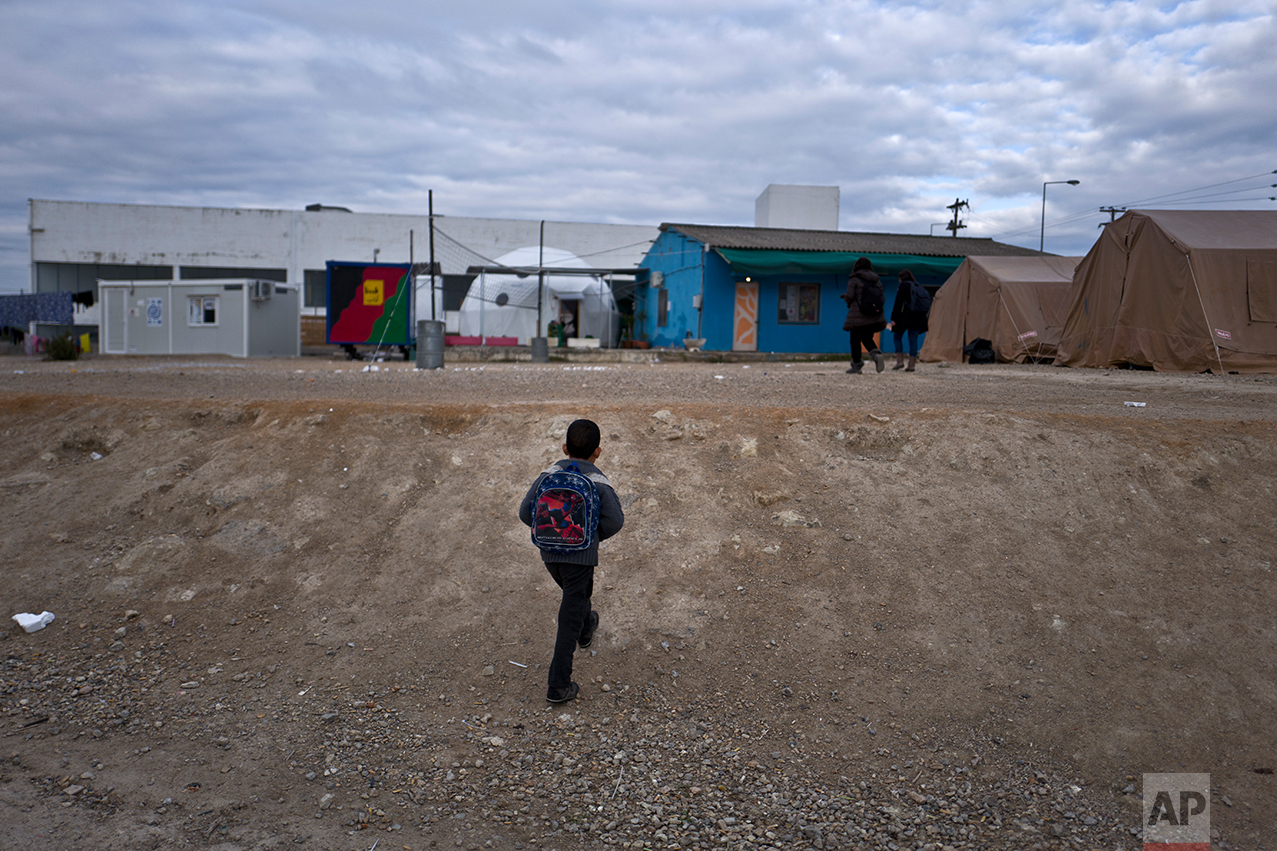  An Afghan refugee boy walks to attend a class at a makeshift school in the refugee camp of Oinofyta about 58 kilometers (36 miles) north of Athens, Tuesday, Dec. 27, 2016. (AP Photo/Muhammed Muheisen) 