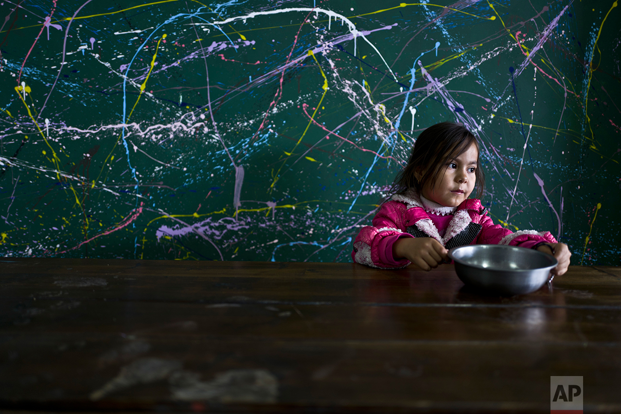  Afghan refugee Setayesh Hassan, 5, sits around a table after eating her lunch at the refugee camp of Oinofyta, about 58 kilometers (36 miles) north of Athens, Monday, Dec. 26, 2016. (AP Photo/Muhammed Muheisen) 