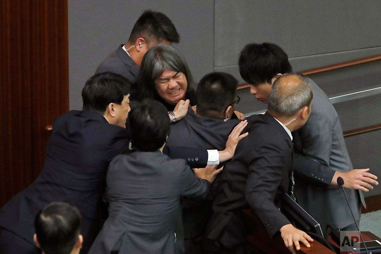  Newly elected pro-democracy lawmaker Leung Kwok-hung, known as "Long Hair," top center, tries to break through the security guards during the election of president of the Legislative Council in Hong Kong, Wednesday, Oct. 12, 2016.  (AP Photo/Kin Che