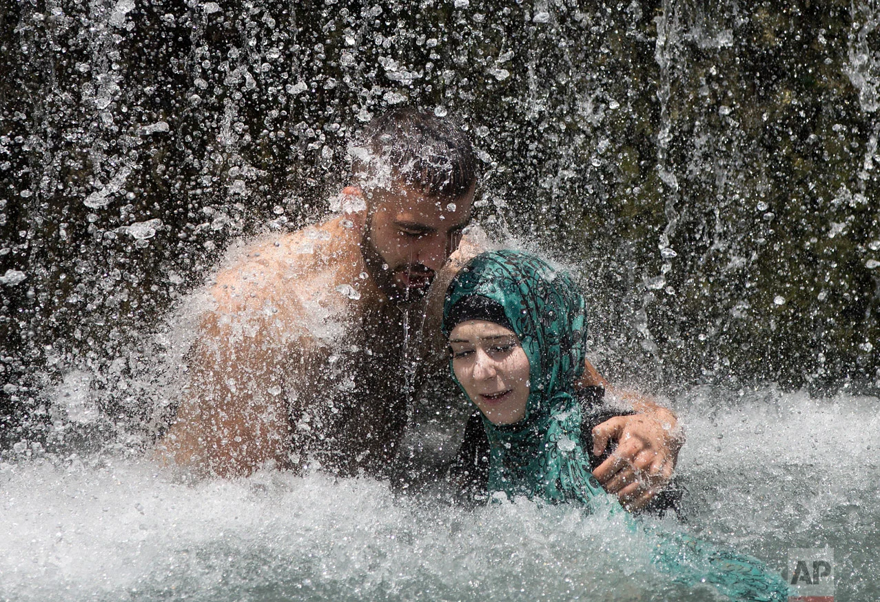 Israeli Arabs stand under a waterfall during the Eid al-Fitr holiday at the Gan HaShlosha national park near the northern Israeli Town of Beit Shean, Friday, July 8, 2016. Eid al-Fitr marks the end of the Muslim holy fasting month of Ramadan. (AP Photo/Oded Balilty)