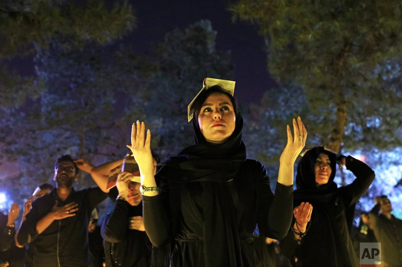 Iranian Shiite Muslims pray as they place the Quran on their heads at the graves of soldiers who were killed during 1980-88 Iran-Iraq War, at the Behesht-e-Zahra cemetery, during the holy fasting month of Ramadan, just outside Tehran, Iran, Monday, June 27, 2016. Iranian Muslims spent the night in prayer and devotion commemorating Laylat Al Qadr, or the Night of Power, which is the anniversary of the night that Muslims believe Prophet Muhammad received the first revelation of the Quran by the angel Gabriel. Ramadan is an Islamic holy month of fasting in which Muslims are expected to abstain from food, drink smoking and sex during daylight and to focus on spirituality, good deeds and charity. (AP Photo/Ebrahim Noroozi)