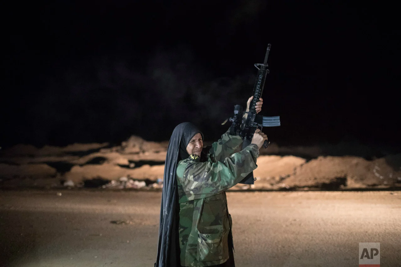 A woman fires into the air at a Popular Mobilization Units base south of Mosul, Iraq, Sunday, Nov. 20, 2016. (AP Photo/Felipe Dana)
