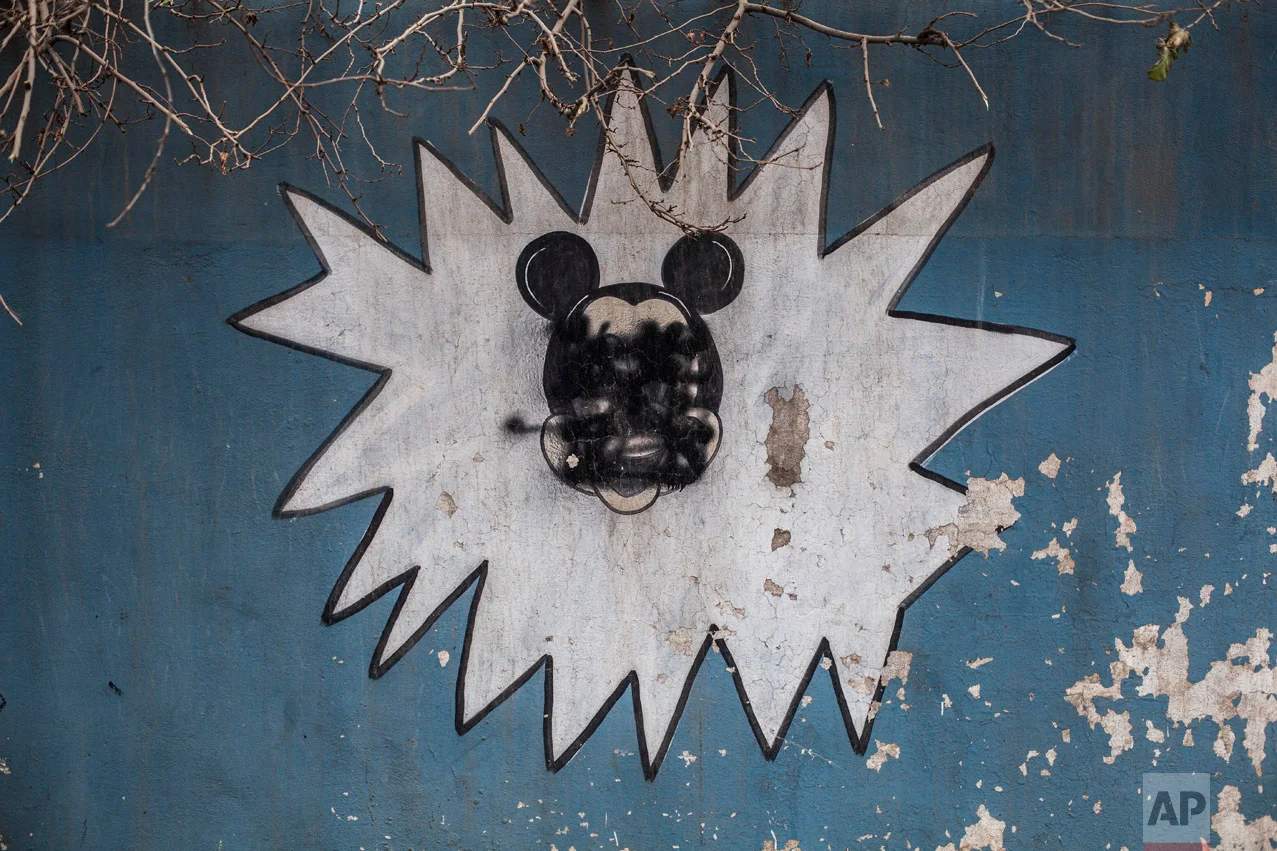 This Sunday, Dec. 18, 2016 photo shows a drawing of Mickey Mouse with its face painted over by Islamic States militants on the wall of a kindergarten n the al-Barid district in Mosul, Iraq. (AP Photo/Manu Brabo)