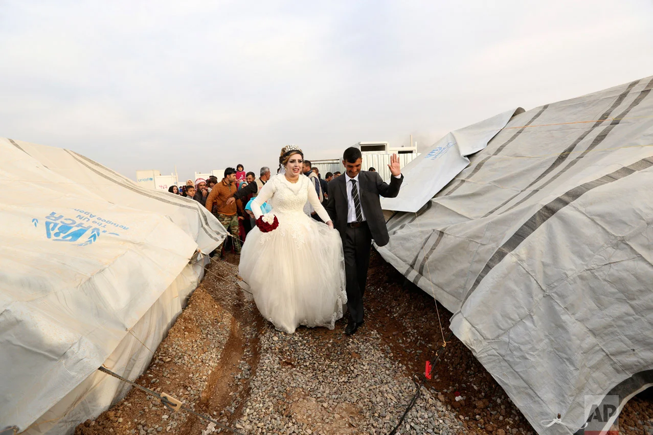 Iraqi internally displaced groom Jassim Mohammed walks with his bride, Amena Ali, during their wedding ceremony at a camp for internally displaced people, in Khazir, near Mosul, Iraq, Thursday, Dec. 8, 2016. (AP Photo/Hadi Mizban)