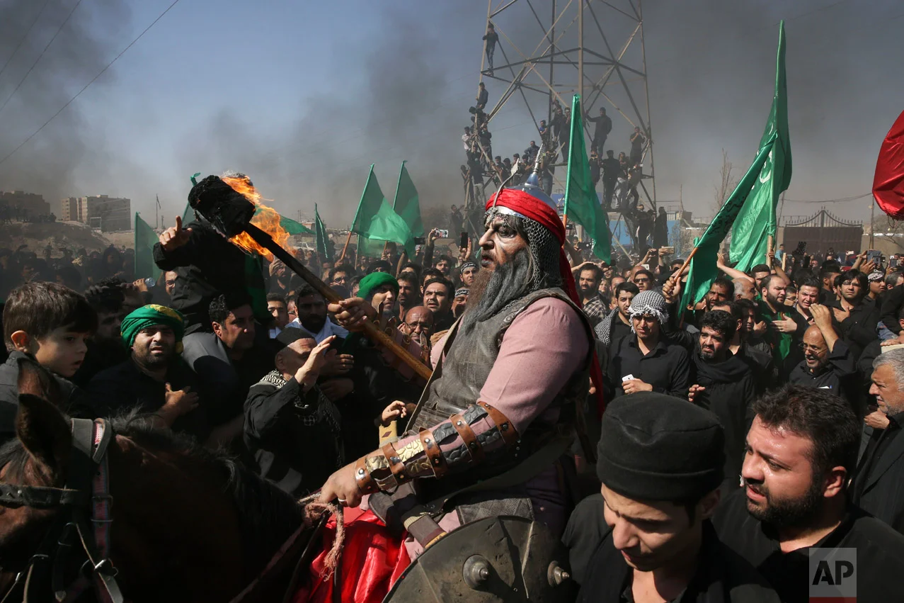 A Shiite re-enacts the events of Ashoura while Iranian and Iraqi Shiite Muslims mourn in a procession in southern Tehran, Iran, Wednesday, Oct. 12, 2016. Shiites mark Ashoura, the tenth day of the Muslim month of Muharram, to commemorate the martyrdom of Imam Hussein, a grandson of Prophet Muhammad and one of Shiite Islam's most beloved saints, during the 7th century Battle of Karbala in present-day Iraq. (AP Photo/Vahid Salemi)