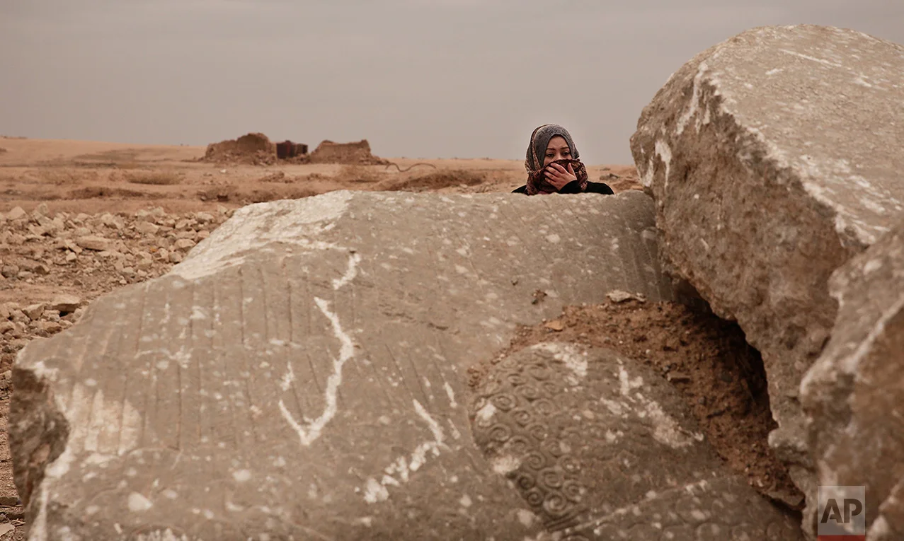 Iraqi archaeologist Layla Salih examines the remains of a statue of a lamassu, a mythical winged bull, destroyed by Islamic State group militants in the ancient site of Nimrud, Iraq, in this Wednesday, Dec. 14, 2016 photo. Salih is perhaps the only vigilant guardian left for the ruins: Since the militants were driven out more than a month ago, she has visited multiple times, trying to prevent looting of the wreckage. (AP Photo/Maya Alleruzzo)