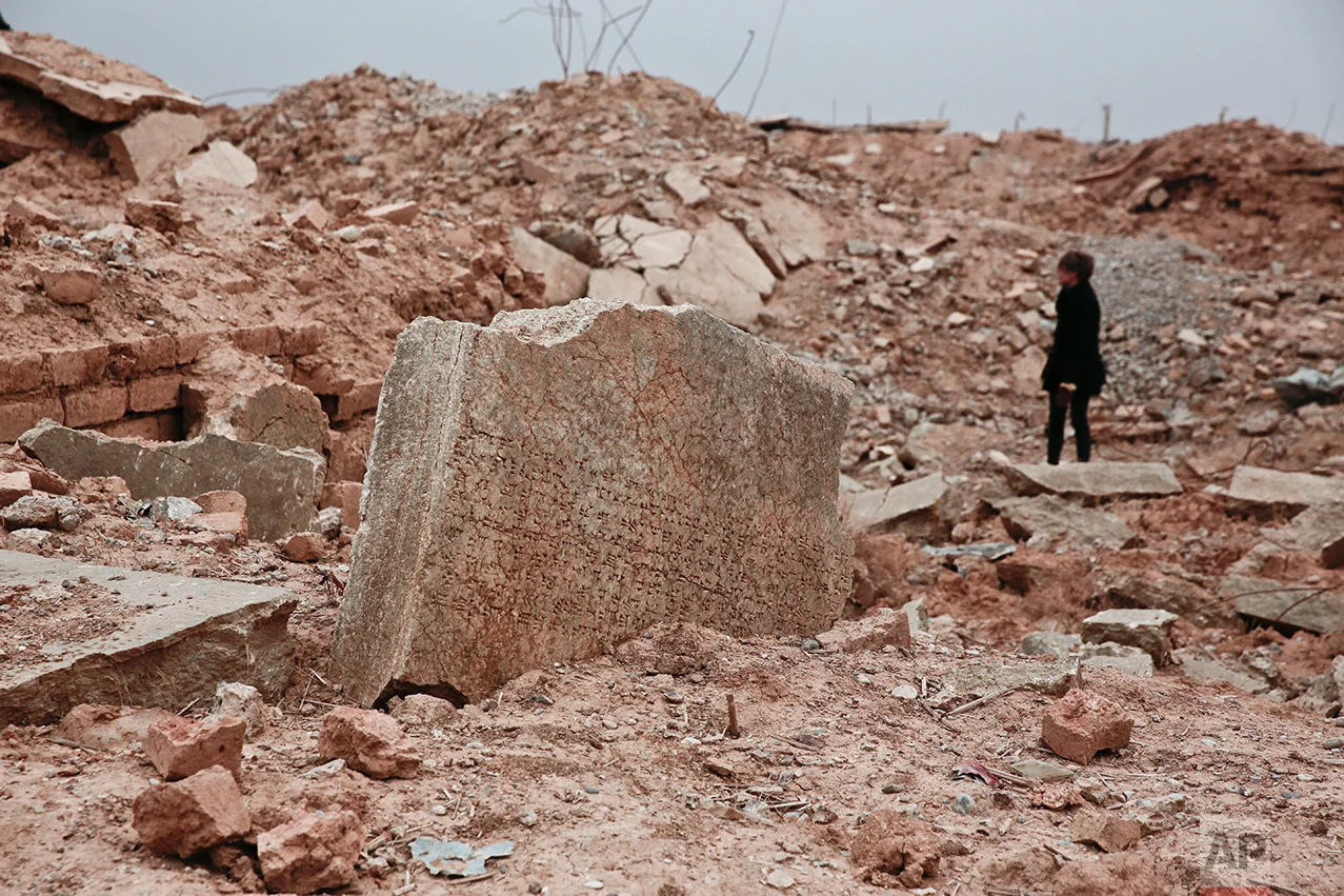 A stone tablet with cuneiform writing is seen in the foreground as UNESCO's Iraq representative Louise Haxthausen documents the damage wreaked by the Islamic State group at the ancient site of Nimrud, Iraq in this Wednesday, Dec. 14, 2016 photo. One of the Mideast’s most important archaeological sites, the nearly 3,000-year-old remains of an Assyrian capital had been a trove of ancient Mesopotamian art and, with hundreds of clay tablets, provided archaeologists a wealth of information on the era. (AP Photo/Maya Alleruzzo)