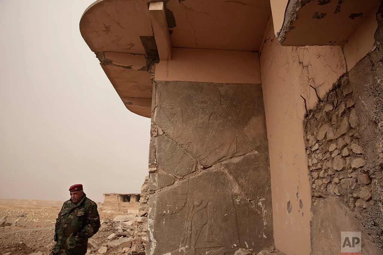 An Iraqi Army general stands near a stone slab depicting a winged genie at the entrance to the Northwest Palace at the ancient site of Nimrud, Iraq in this Wednesday, Dec. 14, 2016 photo. The Islamic State group militants who destroyed the remains of the nearly 3,000-year-old city have been driven away. But with the war still raging nearby, no one has been assigned to guard the site and the wreckage strewn around it is vulnerable to looting. (AP Photo/Maya Alleruzzo)