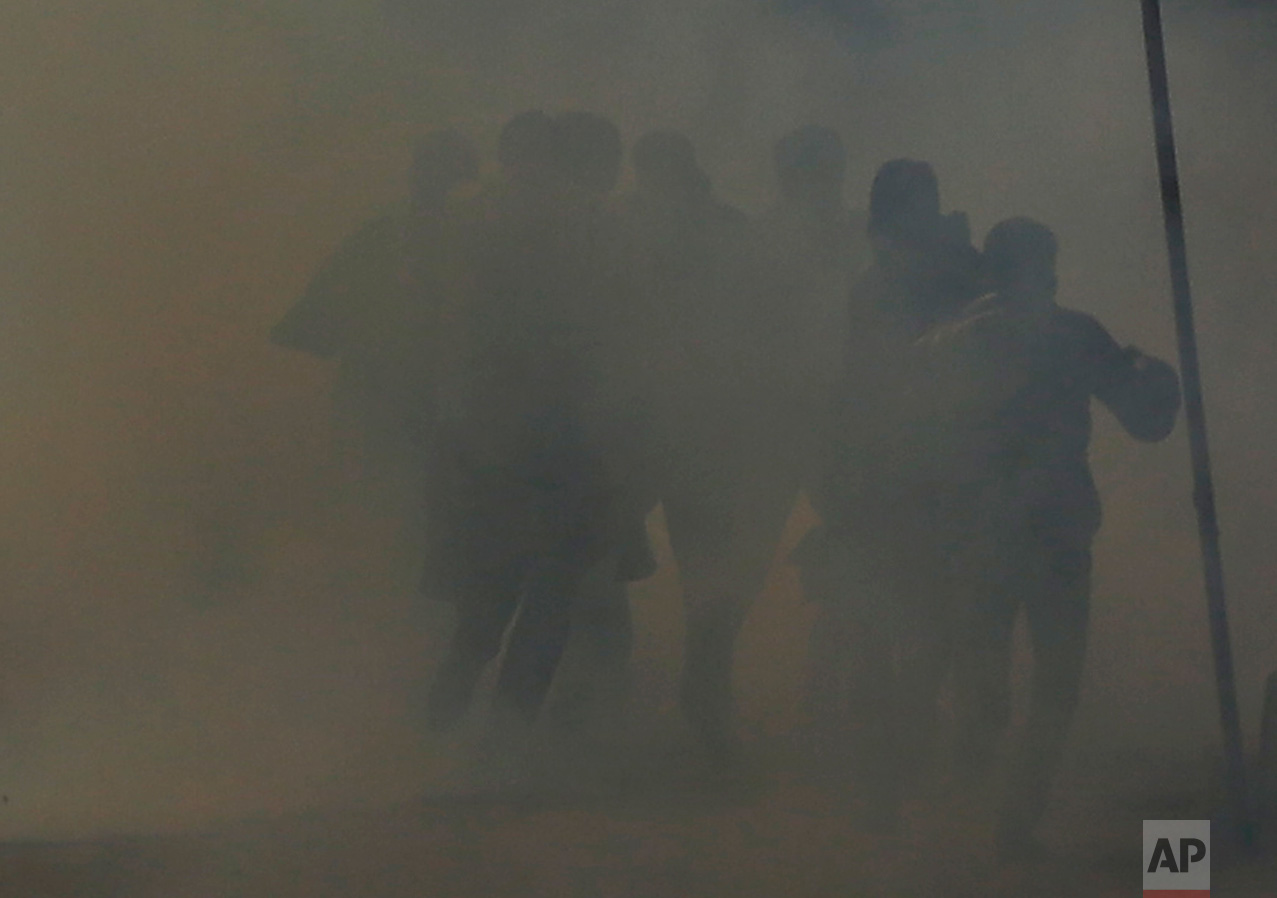 Kashmiri protesters run for cover from tear gas during a protest after Friday prayers in Srinagar, Indian-controlled Kashmir, on Friday, Dec. 30, 2016. Police fired tear gas and shotgun pellets to disperse demonstrators who gathered to protest Indian rule in the disputed region. (AP Photo/Mukhtar Khan)