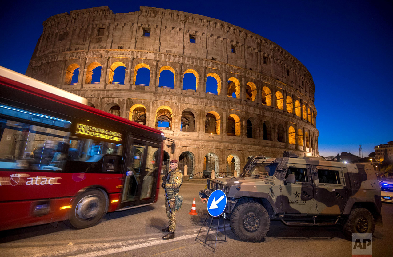 A bus drives past a soldier patrolling the ancient Colosseum area in Rome on Wednesday, Dec. 28, 2016. Italy has been strengthening security measures for areas where crowds are expected. (Claudio Peri/ANSA via AP)
