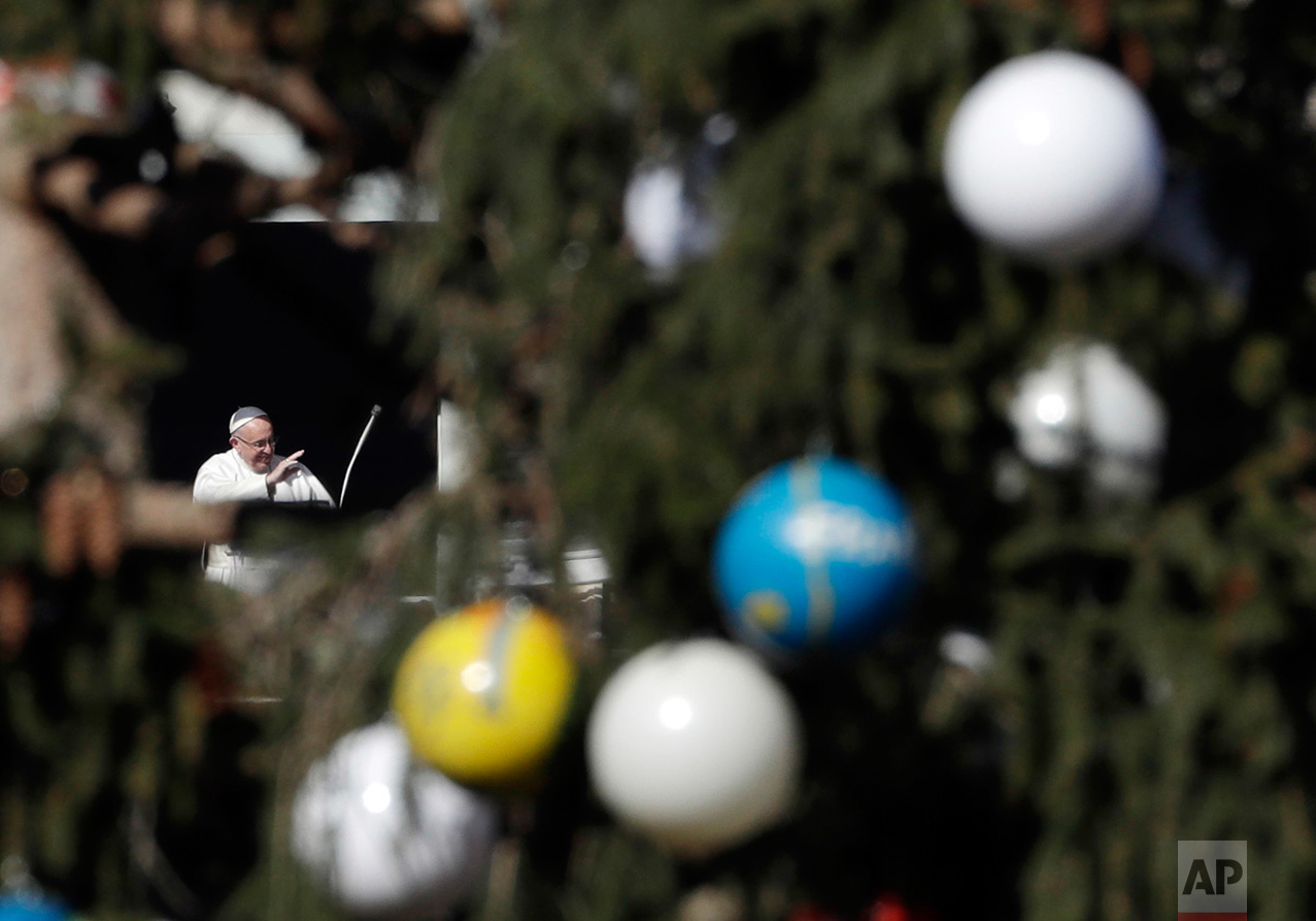 Framed by a Christmas tree, Pope Francis waves to worshippers during the Angelus noon prayer which he delivered from his studio window overlooking St. Peter's Square at the Vatican, on Monday, Dec. 26, 2016. Speaking to thousands gathered to celebrate the feast day of St. Stephen, the first Christian martyr, Francis expressed his ''strong condolences'' to the Russian people and to those who lost loved ones in a military plane which crashed shortly after take off from the city of Sochi on Sunday. (AP Photo/Gregorio Borgia)