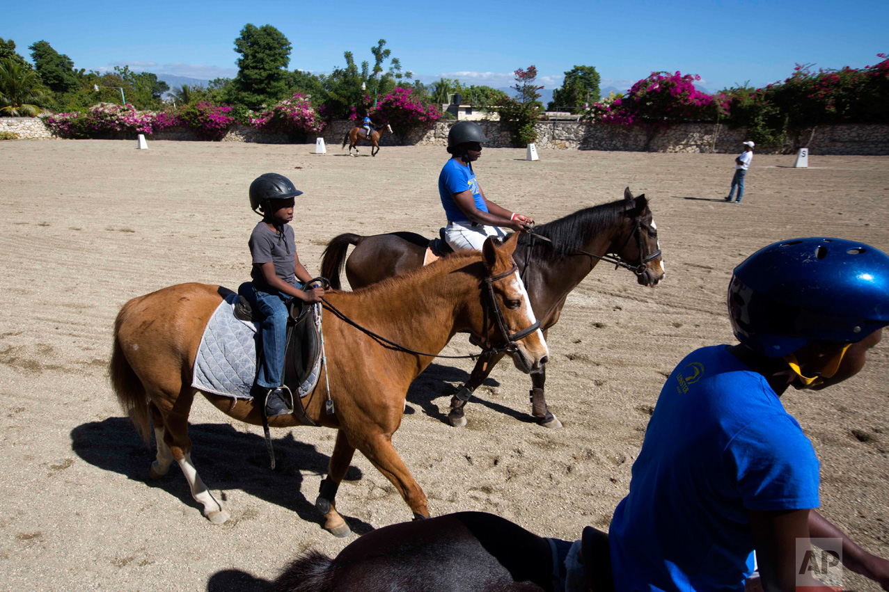 In this Jan. 11, 2017 photo, Judeley Hans Debel, left, who's right leg is a prosthesis, rides Tic Tac at the Chateaublond Equestrian Center in Petion-Ville, Haiti. Judeley plays soccer and other games with schoolmates and hopes to study medicine when he's older, but his favorite activity is unquestionably riding Tic Tac, a roughly 32-year-old mare with a sweet disposition. His rapport with the animal was nearly immediate. (AP Photo/Dieu Nalio Chery)