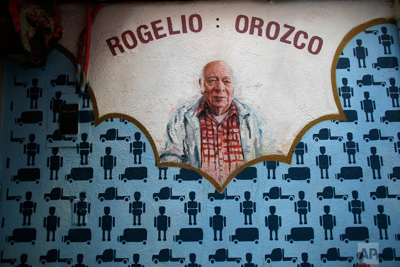 In this Jan. 11, 2017 photo, a mural painted by South African artist Christiaan Conradie depicting Mexican toymaker Rogelio Orozco graces a wall of the Mexico Antique Toy Museum in Mexico City. Orozco continues to make toy trucks and trains made out of tin with electric motors. The museum reminds Mexicans of their rich cultural heritage as well as a blunt reminder that before the North American Free trade agreement was signed in the 1990's, Mexico had a robust, healthy and creative national toy industry that is now practically defunct.(AP Photo/Dario Lopez-Mills)