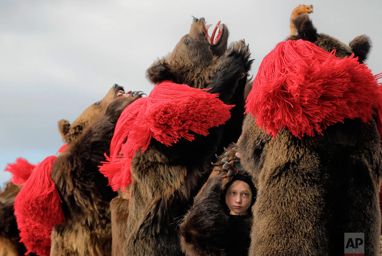 A child wearing a bear fur costume dances along with adults during the annual bear ritual gathering in Comanesti, Romania, Friday, Dec. 30, 2016. In pre-Christian rural traditions, dancers wearing colored costumes or animal furs, toured from house to house in villages singing and dancing to ward off evil. In the present, the tradition has moved to Romania's cities too, where dancers travel to perform the ritual for money. (AP Photo/Vadim Ghirda)