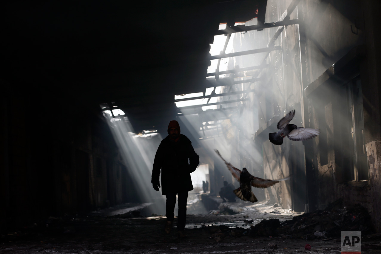 In this Thursday, Jan. 12, 2017 photo, a migrant walks through a crumbling warehouse that has served as a make-shift shelter for hundreds of men wishing to reach Western Europe, in Belgrade, Serbia. (AP Photo/Darko Vojinovic)