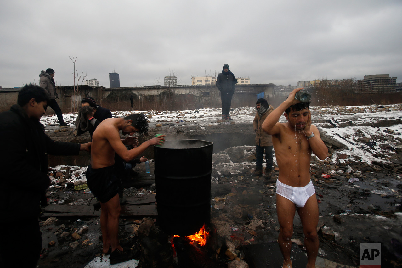 In this Saturday, Jan. 14, 2017 photo, migrants wash themselves outside a crumbling warehouse that has served as a makeshift shelter in Belgrade, Serbia. (AP Photo/Darko Vojinovic)