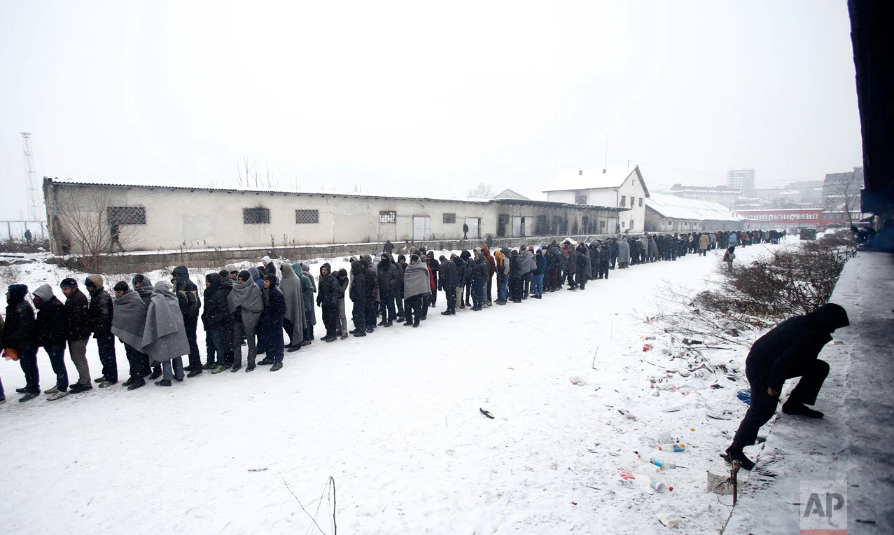 In this Tuesday, Jan. 10, 2017 photo, migrants queue for food in front of an abandoned warehouse in Belgrade, Serbia. (AP Photo/Darko Vojinovic)