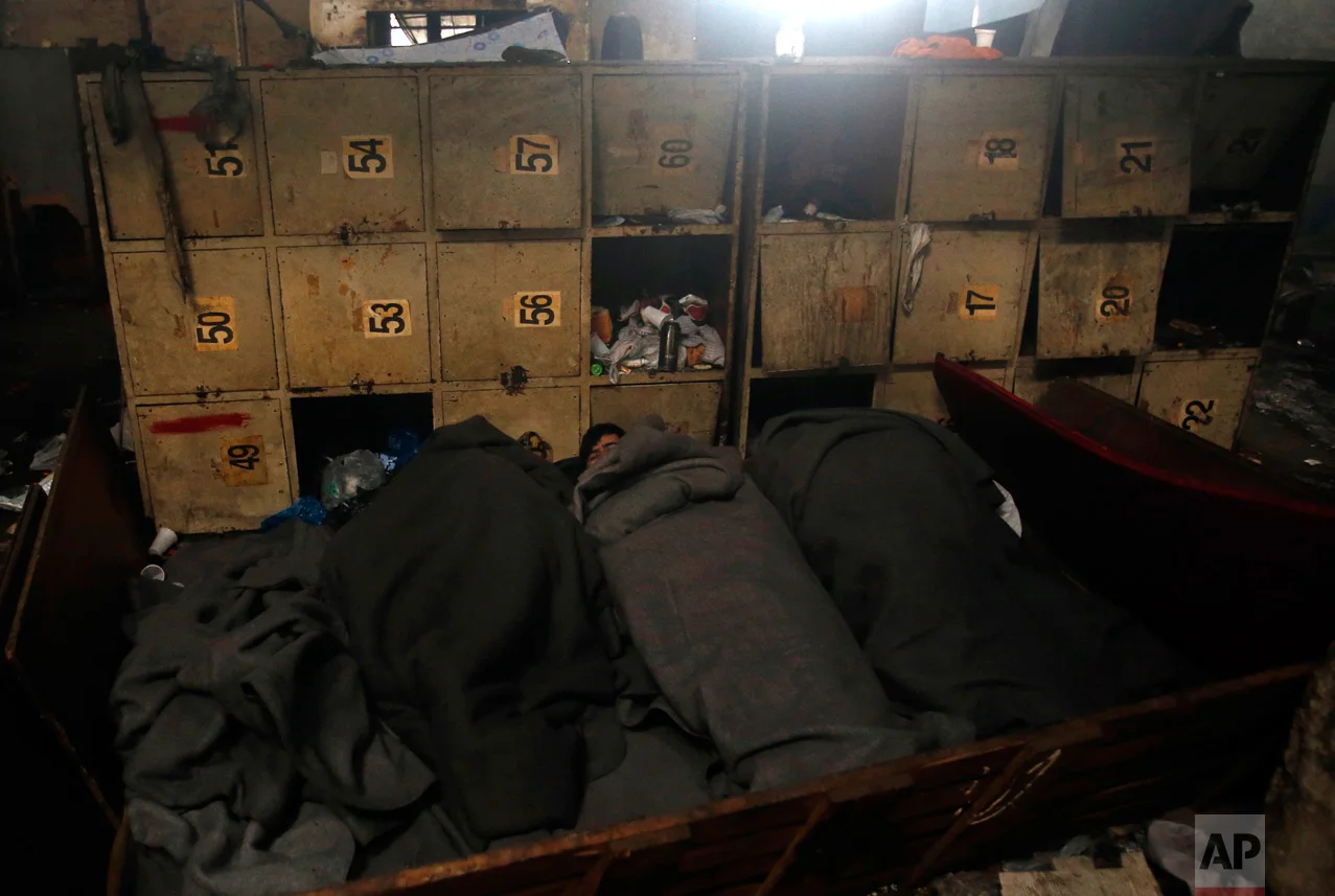 In this Thursday, Jan. 12, 2017 photo, migrants sleep inside a crumbling warehouse that has served as a make-shift shelter for hundreds of men trying to reach Western Europe in Belgrade, Serbia. Wrapped in blankets, people huddled next to each other desperately trying to keep warm by the fires they lit inside and outside the building. (AP Photo/Darko Vojinovic)