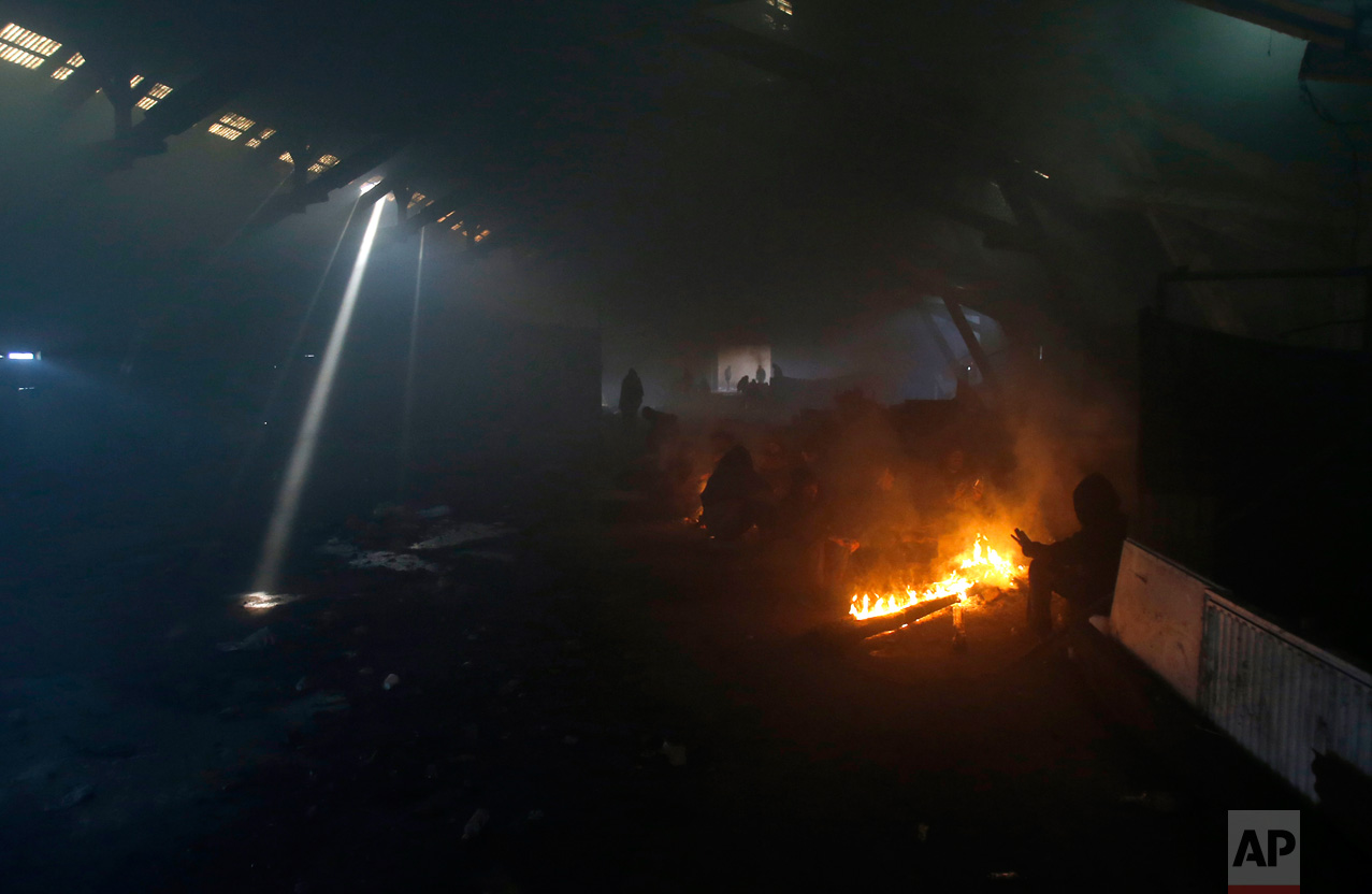 In this Sunday, Jan. 8, 2017 photo, migrants warm themselves by the fire in an abandoned warehouse in Belgrade, Serbia. It was a week in frigid hell for hundreds of migrants squatting in an abandoned warehouse in the Serbian capital of Belgrade while trying to move on toward Western Europe. (AP Photo/Darko Vojinovic)