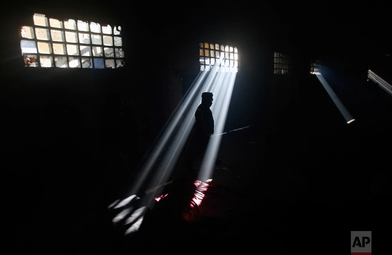 In this Sunday, Jan. 8, 2017 photo, a migrant stands in an abandoned warehouse in Belgrade, Serbia. When the weather suddenly turned nasty it sent temperatures plummeting way below zero and cold wind started to blow pushing into every corner of make-shift migrant shelter. (AP Photo/Darko Vojinovic)