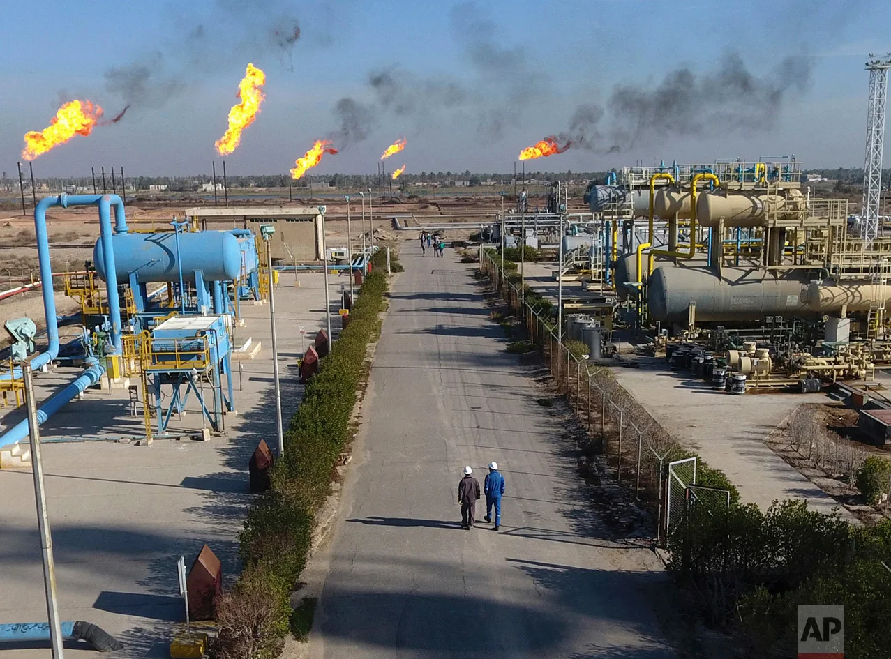 Laborers walk down a path in the Nihran Bin Omar field north of Basra, Iraq, 340 miles (550 kilometers) southeast of Baghdad, on Thursday, Jan. 12, 2017. Iraq's state-run South Gas Company inaugurated a gas pipeline to transport gas, a by-product of oil production, from Nihran Bin Omar field to the national network. (AP Photo/Nabil al-Jurani)