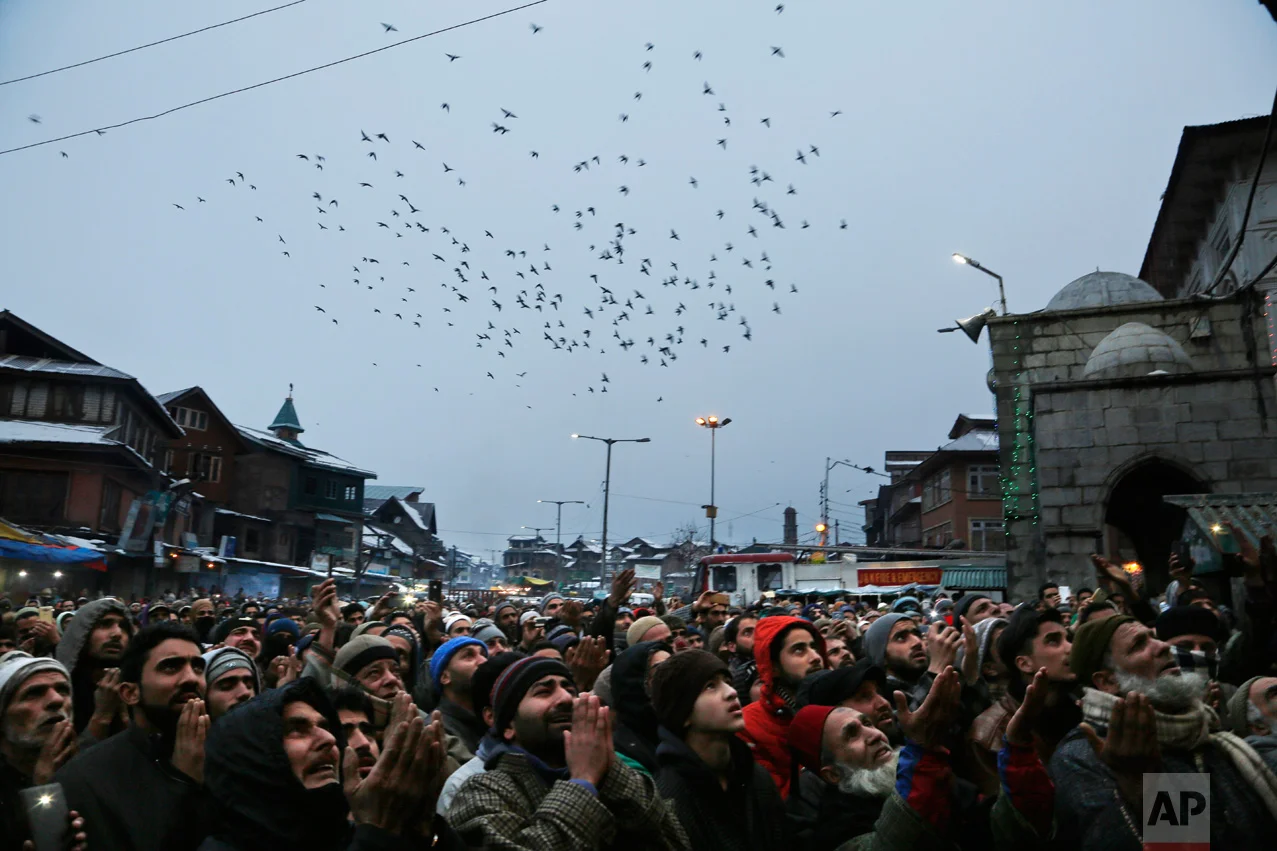 A flock of birds fly past Kashmiri Muslim devotees praying during a display of a relic of Sufi saint Syed Abdul Qadir Jilani at his shrine in Srinagar in Indian-controlled Kashmir, Tuesday, Jan. 10, 2017. Thousands thronged the shrine Tuesday to mark the saint's Urs, an annual commemoration. (AP Photo/Mukhtar Khan)