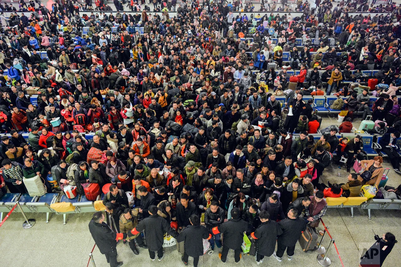 Railway workers hold back passengers at the Hankou Railway Station in Wuhan on the eve of the annual Spring Festival travel rush in central China's Hubei province on Thursday, Jan. 12, 2017. Officials expect that travelers will make almost 3 billion trips during the holiday travel rush that starts Friday and runs through Feb. 21. These trips include intercity flights, trains and local bus rides to villages. (Chinatopix Via AP)