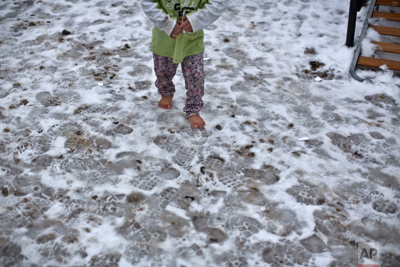 A Syrian refugee child walks barefoot on frozen ground at the Ritsona, Greece refugee camp, about 86 kilometers (53 miles) north of Athens, on Wednesday, Jan. 11, 2017. The European Commission said conditions for refugees on islands and other camps where they are housed in tents in severe cold weather is "untenable." (AP Photo/Muhammed Muheisen)