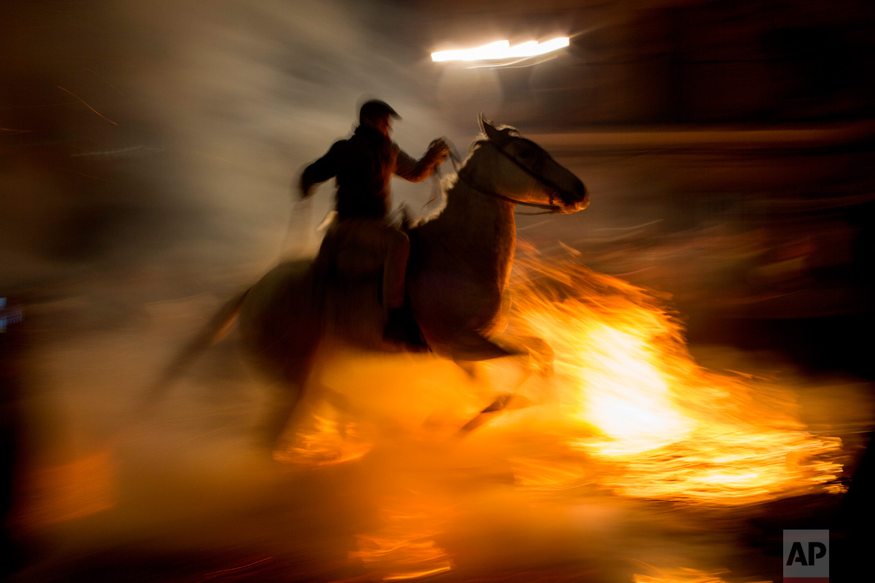A man rides a horse through a bonfire as part of a ritual in honor of Saint Anthony the Abbot, the patron saint of domestic animals, in San Bartolome de Pinares, about 100 km west of Madrid, Spain, on Monday, Jan. 16, 2017. (AP Photo/Emilio Morenatti)