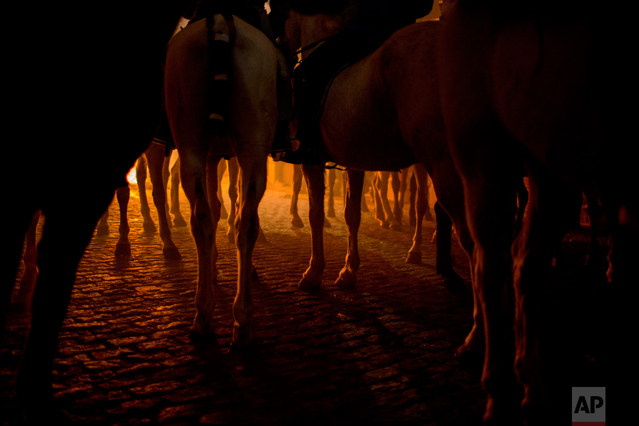 Men ride horses next to a bonfire as part of a ritual in honor of Saint Anthony the Abbot, the patron saint of domestic animals, in San Bartolome de Pinares, about 100 km west of Madrid, Spain on Monday, Jan. 16, 2017. (AP Photo/Emilio Morenatti)