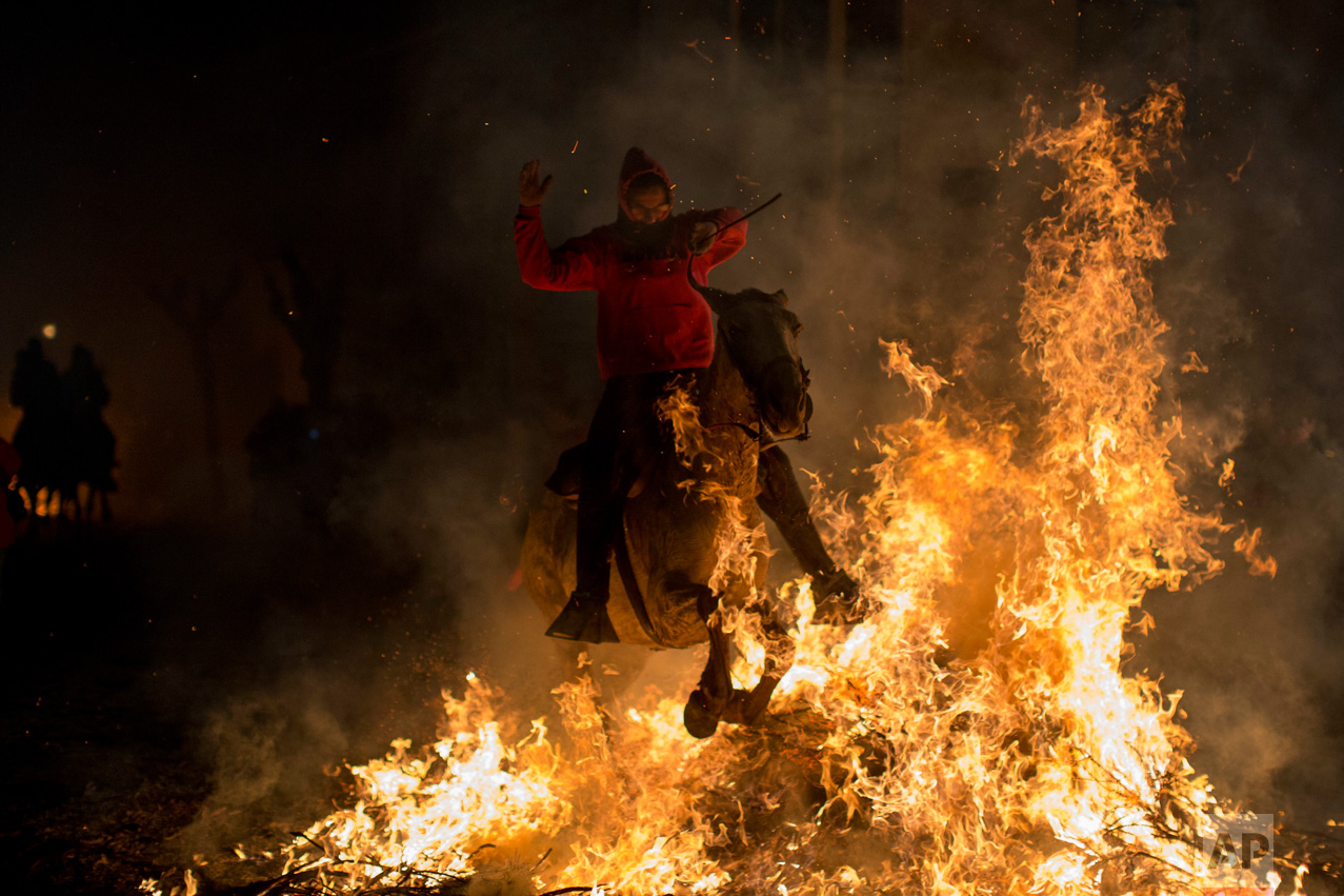 A man rides a horse through a bonfire as part of a ritual in honor of Saint Anthony the Abbot, the patron saint of domestic animals, in San Bartolome de Pinares, about 100 km west of Madrid, Spain on Monday, Jan. 16, 2017. (AP Photo/Emilio Morenatti)
