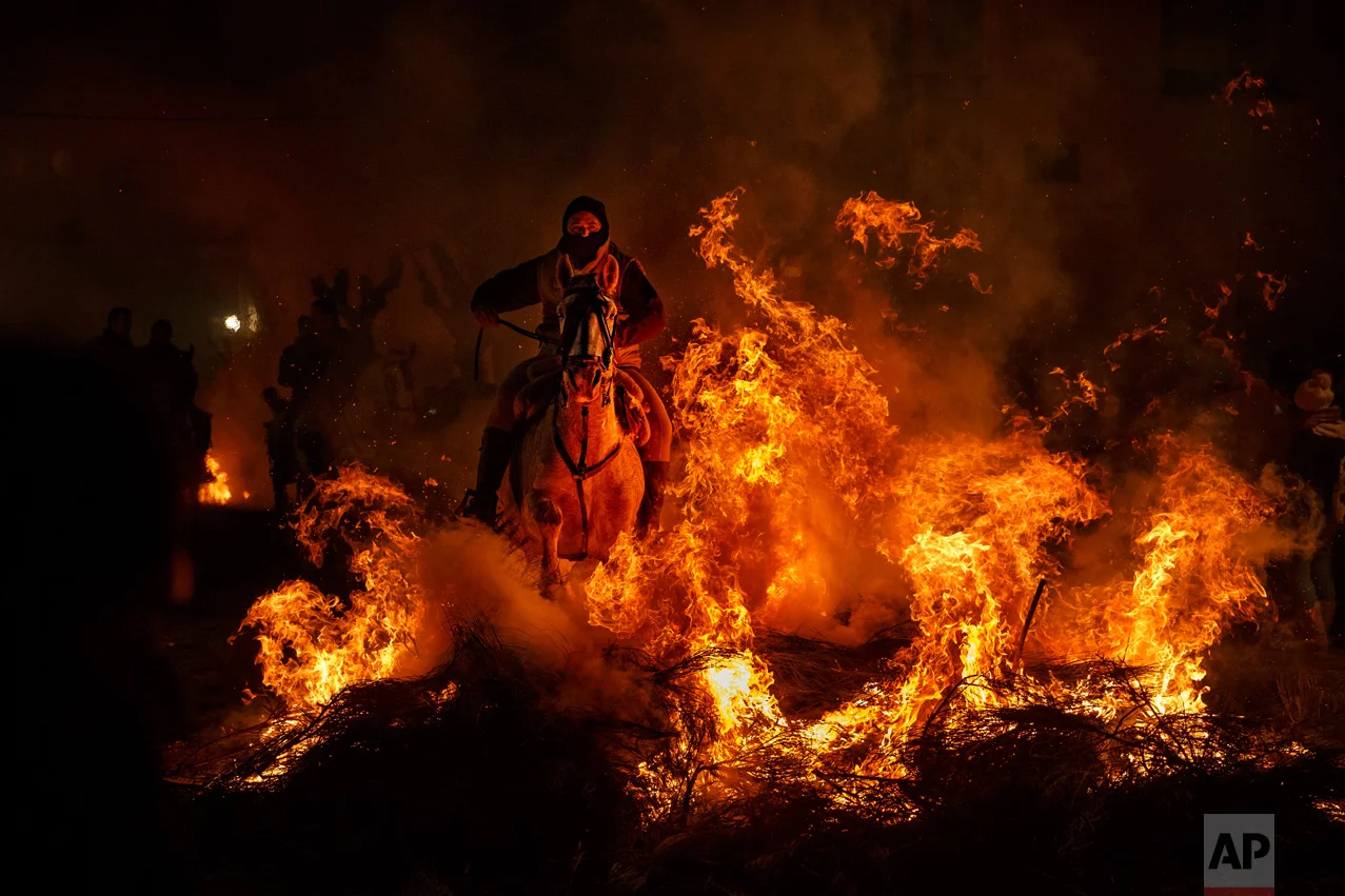 A man rides a horse through a bonfire as part of a ritual in honor of Saint Anthony the Abbot, the patron saint of domestic animals, in San Bartolome de Pinares, west of Madrid, Spain on Monday, Jan. 16, 2017. (AP Photo/Daniel Ochoa de Olza)