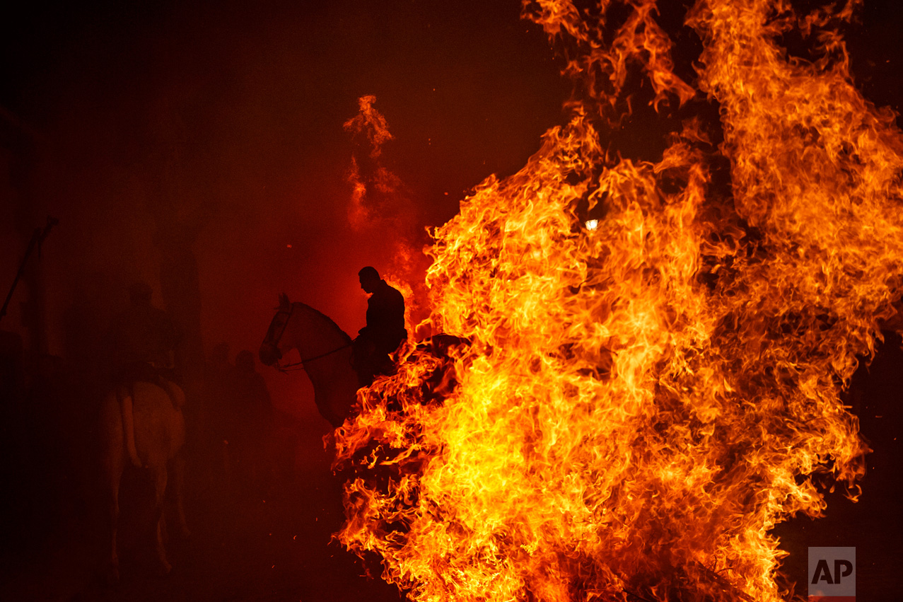 A man rides a horse by a bonfire as part of a ritual in honor of Saint Anthony the Abbot, the patron saint of domestic animals, in San Bartolome de Pinares, west of Madrid, Spain on Monday, Jan. 16, 2017. (AP Photo/Daniel Ochoa de Olza)