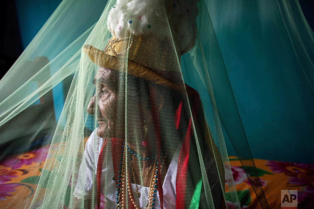This Dec. 19, 2016 photo shows Clara Padilha Gomes preparing spiritually for the Marujada religious celebration, in honor of St. Benedict, at her home in the fishing town of Braganca, Brazil. Gomes, 77, said she participates to give thanks for her son. "As long as I'm alive, I will be devoted," she said. "A person has to have faith." (AP Photo/Eraldo Peres)