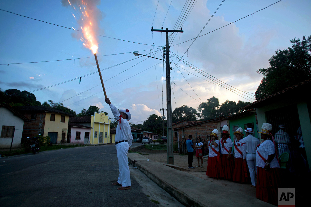This Dec. 26, 2016 photo shows captain Jose Batista launching a firecracker during Marujada religious celebrations in honor of St. Benedict in the fishing town of Braganca, Brazil. The tradition started when black slaves persuaded their masters to let them form a brotherhood to pay homage to St. Benedict. (AP Photo/Eraldo Peres)