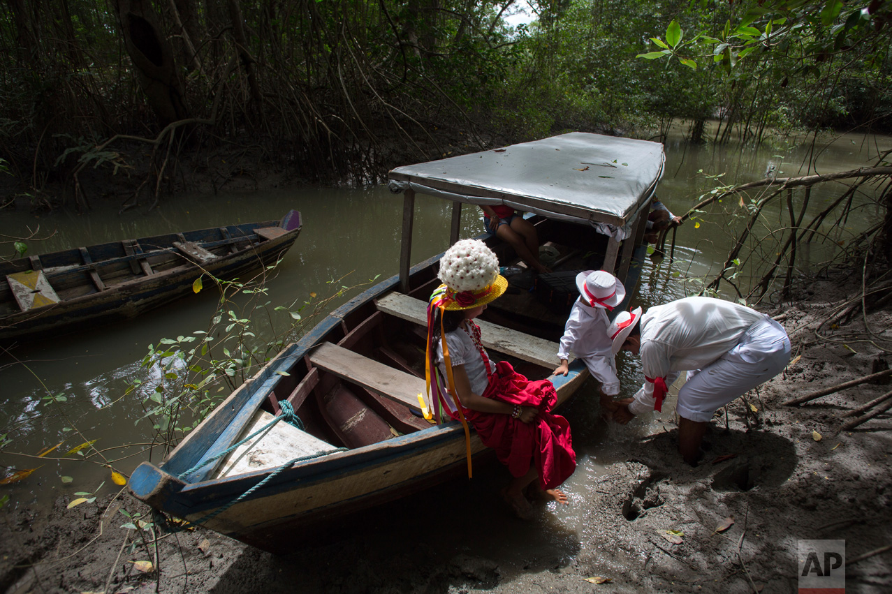 This Dec. 20, 2016 photo shows a family arriving on the Caete River to attend Marujada religious celebrations in honor of St. Benedict in the fishing town of Braganca, Brazil. Locals say the annual celebration, which started in 1798, is a way to show appreciation and make good on promises for miracles received. (AP Photo/Eraldo Peres)