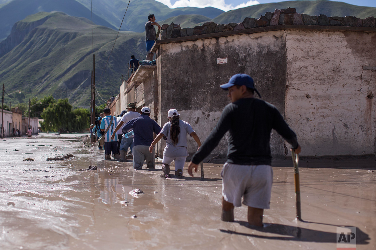 In this Jan. 13, 2017 photo, volunteers walk with shovels on the way to help clear clear the mud and help locals the town of Volcan, Jujuy province, Argentina. The mudslide was caused by the intense rains that hit the area one week ago, flooding the town with mud, killing several and causing the evacuation of thousands. (Gianni Bulacio/Infoto via AP)