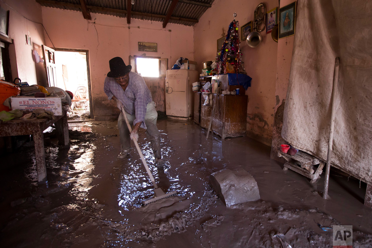 In this Jan. 13, 2017 photo, a resident begins the clean up of his mud damaged home in the town of Volcan, Jujuy province, Argentina. That town was hit by a mudslide a week ago after heavy rains blanketed the area. (Gianni Bulacio/Infoto via AP)