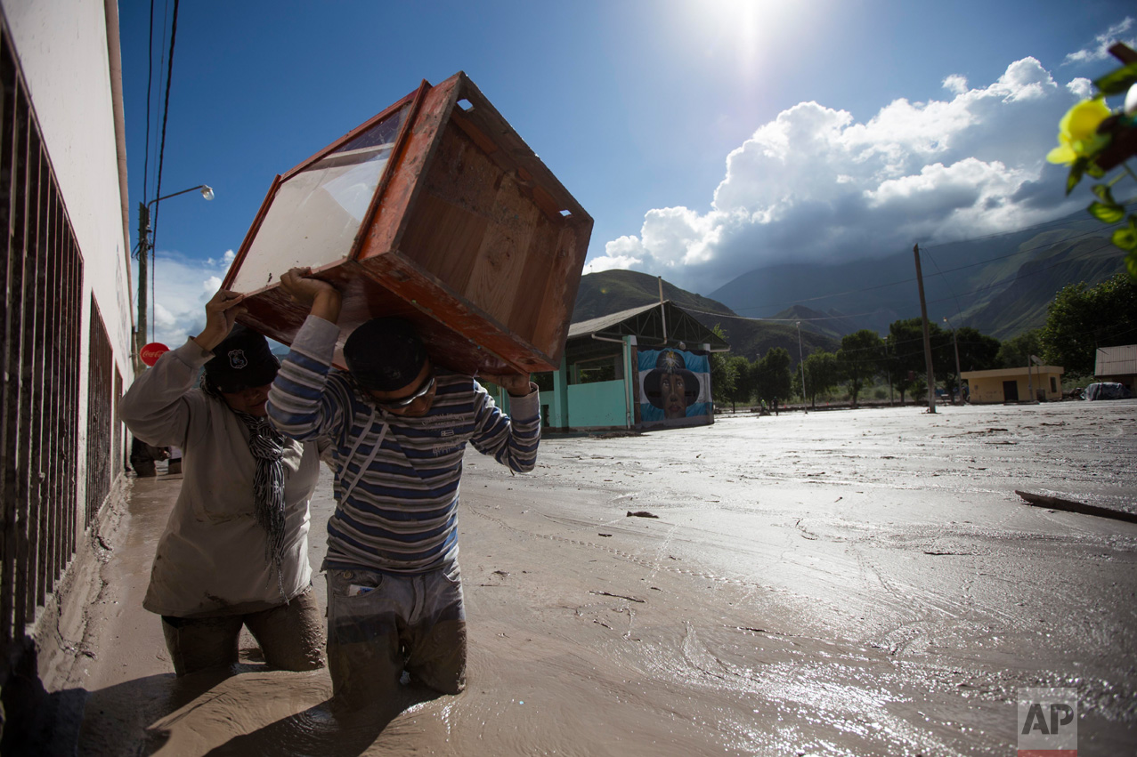 In this Jan. 13, 2017 photo, residents carry rescued religious figures through the mud covered streets of the town of Volcan, Jujuy province, Argentina. The statues will be taken to a secure place until cleanup efforts are completed in the mud covered town. (Gianni Bulacio/Infoto via AP)